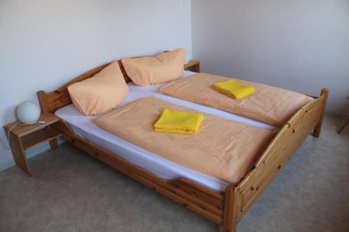 a wooden bed with two yellow pillows on it at Ferienhof Rügen in Maltzien