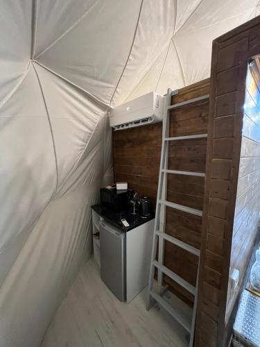 卡拉科爾的住宿－GLAXY_GLAMPING，帐篷内的房间,配有炉灶和梯子