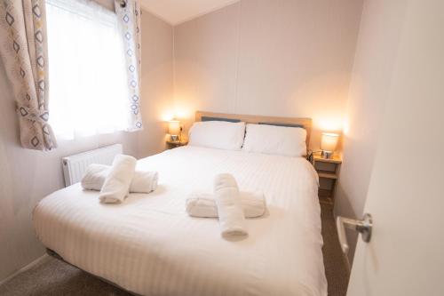 a bedroom with a white bed with towels on it at Marine Holiday Park in Rhyl