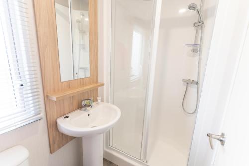 a white bathroom with a sink and a shower at Marine Holiday Park in Rhyl
