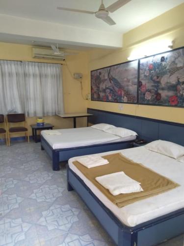 a room with two beds and a chair in it at hotel chaitanya international in Puttaparthi