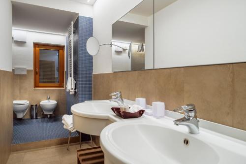 La salle de bains est pourvue d'un lavabo, de toilettes et d'un miroir. dans l'établissement Barisetti Sport Hotel, à Cortina dʼAmpezzo