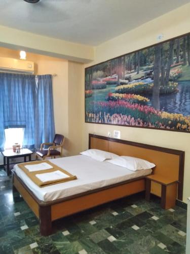 a bedroom with a bed and a painting on the wall at hotel chaitanya international in Puttaparthi