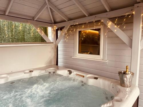 una bañera de hidromasaje en una casa con ventana en The Retreat Cabin, en Pitlochry