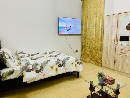 a bedroom with a bed with a tv on the wall at Relaxation Quiet Room 2 in Abu Dhabi