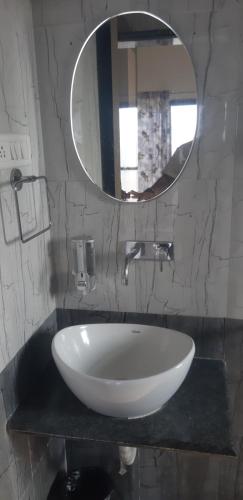 uma casa de banho com um lavatório branco e um espelho. em Hotel The Grand em Mahabaleshwar