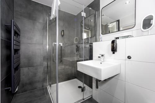 a white bathroom with a sink and a shower at Hotel Deluxe in Dorsten