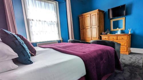 a bedroom with a bed with a purple blanket on it at Villa Marina in Torquay