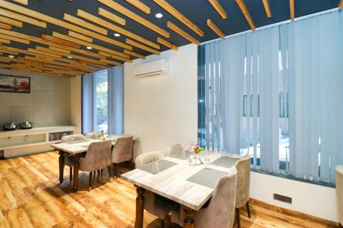 a dining room with a table and chairs and large windows at OPO Hotel Vertu,Free Airport Pick-up in New Delhi