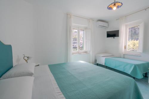 ein weißes Schlafzimmer mit 2 Betten und 2 Fenstern in der Unterkunft Little House in Minori