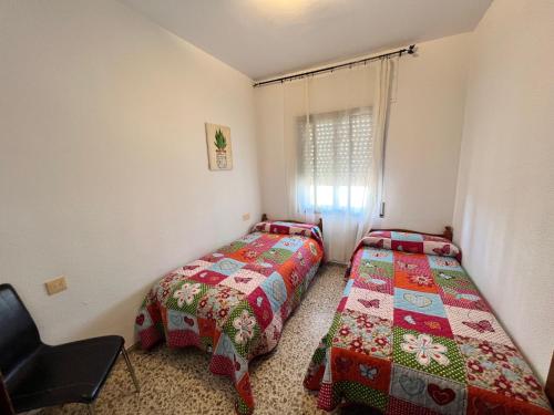1 dormitorio con 2 camas y 1 silla en Vigalpe Valdelagrana 10, en El Puerto de Santa María