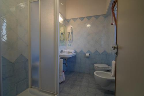 a bathroom with two toilets and a sink and a shower at Hotel Da Ruggero - 100m dal Porto in Giglio Porto
