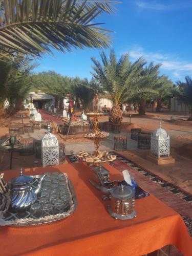 une table avec des assiettes de nourriture et des palmiers dans l'établissement Merzouga Luxury Desert camp, excursion and activities, à Merzouga