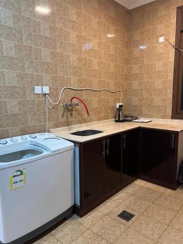 eine Küche mit einer Spüle und einer Waschmaschine in der Unterkunft فيو بلس للشقق الفندقية in Chamis Muschait