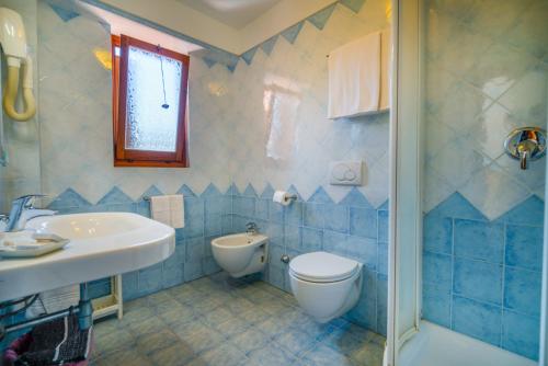 Hotel Da Ruggero في جيليو بورتو: حمام من البلاط الأزرق مع مرحاض ومغسلة