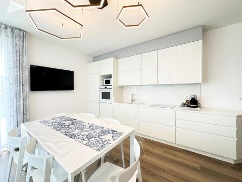 cocina con armarios blancos, mesa y sillas en Magica Immobiliare - Res. Medusa 15, en Lido di Jesolo