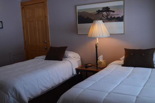two beds in a room with a lamp on a table at Wiley Inn in Peru