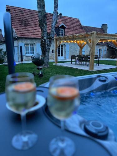 - deux verres de vin assis sur une table dans l'établissement Gîte avec jacuzzi 6 personnes, à Brouchaud