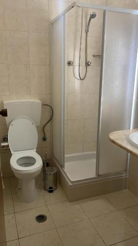 a bathroom with a shower and a toilet and a sink at Felicidade Hotel in Praia