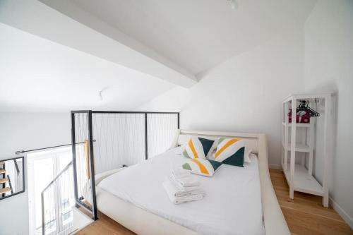 ein weißes Schlafzimmer mit einem Bett und einem Fenster in der Unterkunft PETIT DUPLEX - Nouveau duplex central avec wifi et clim pour 2 in Antibes