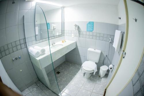 a bathroom with a toilet and a sink and a mirror at Orange Praia Hotel in Itamaracá