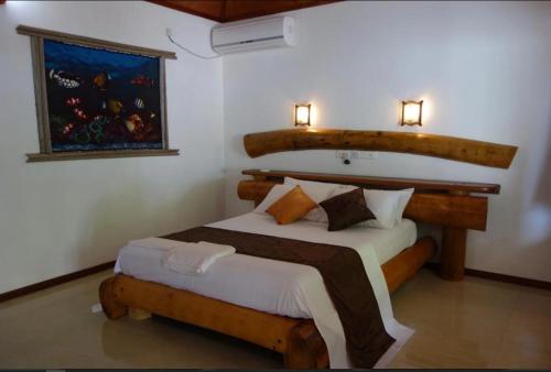 Schlafzimmer mit einem Bett mit einem Kopfteil aus Holz in der Unterkunft RAINIKA VILLA in Thinadhoo