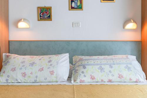 a bed with two pillows and two pictures on the wall at Hotel Atlantic in Gatteo a Mare