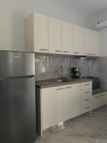 a kitchen with white cabinets and a stainless steel refrigerator at DiaMar in Kallithea Halkidikis