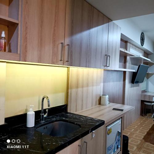 una cocina con fregadero y armarios de madera en Apartment Louise kienne, en Semarang