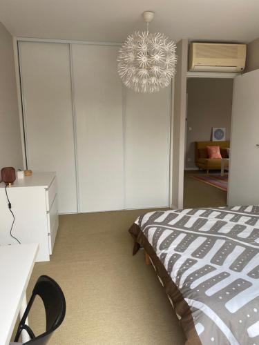 Schlafzimmer mit einem Bett und einem Kronleuchter in der Unterkunft Chambre Serenity in Brignais