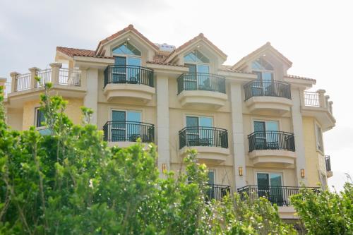 a tall yellow building with balconies and trees at Island on the Sea in Kenting