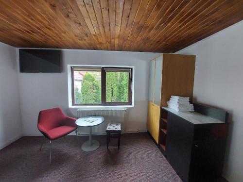 Zimmer mit einem roten Stuhl, einem Tisch und einem Fenster in der Unterkunft The Black Cat in Bran