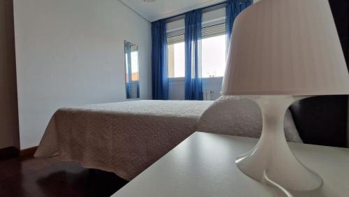 a bedroom with a bed and a lamp on a table at Chalet Adosado con jardín in Cóbreces