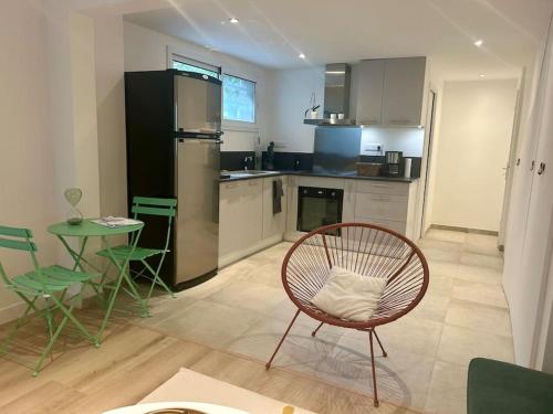 a kitchen with a rattan chair and a table and a counter at Nice new apartment with direct access a big garden in Saint-Germain-en-Laye