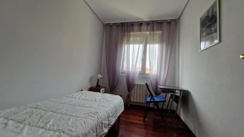 a bedroom with a bed and a desk and a window at Chalet Adosado con jardín in Cóbreces