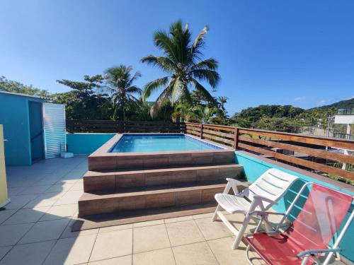 a swimming pool with stairs and two chairs on a patio at Pousada Sereia Tropical in Guarujá