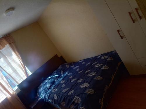 ein Schlafzimmer mit einem Bett mit blauer Decke und einem Fenster in der Unterkunft Moderno y acogedor apartamento con vista al jardin in Lima
