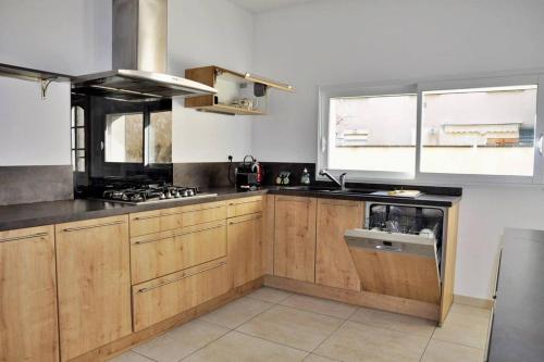 une cuisine avec des armoires en bois et un four à plaques de cuisson dans l'établissement Villa Beaumont, à Bourges