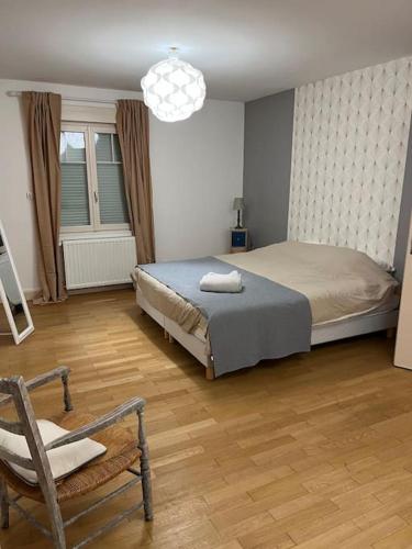 - une chambre avec un lit, une chaise et un lustre dans l'établissement Villa Beaumont, à Bourges