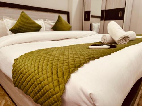 a bed with a green blanket on it at Aston Hills Rooms & Cottages Tapovan in Rishīkesh