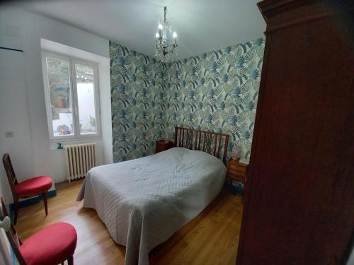 een slaapkamer met een bed, een stoel en een raam bij La maison du jardin in Saint-Jean-de-Luz