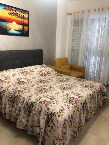 um quarto com uma cama com uma colcha floral e uma cadeira em Apartamento di Kian em Golem