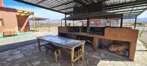 a outdoor grill with a wooden table and a table and bench at La Comarca in Uspallata