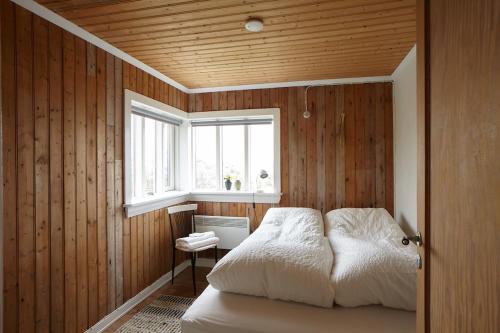 a bedroom with wooden walls and a bed with a window at Guesthouse Nýp in Nýp