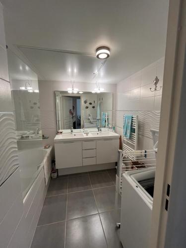 une salle de bain avec un lavabo et un grand miroir dans l'établissement Charmant F3 vue mer avec piscine, à Bandol