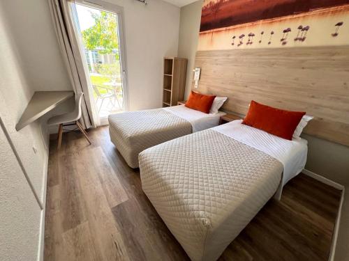 アルルにあるHôtel le Mas des Ponts d'Arlesの大きな窓付きの客室で、ベッド2台が備わります。