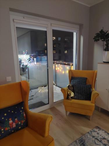 uma sala de estar com uma cadeira amarela e uma janela em Apartament Ząbki em Zabki
