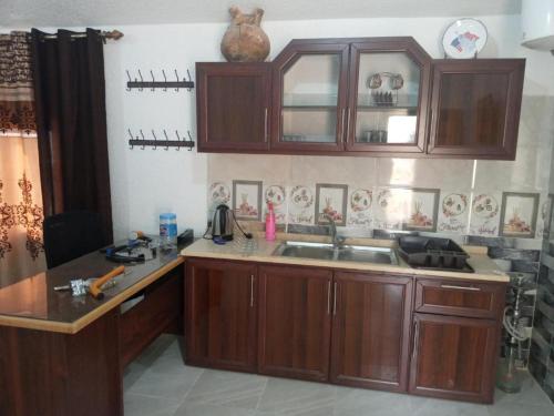 una cocina con armarios de madera y fregadero en Jerash Roman Gate Shalea شاليه بوابة جرش الرومانيه الشماليه, en Jerash
