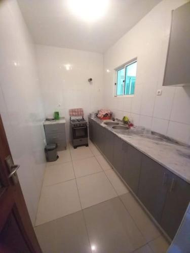 a white kitchen with a sink and a stove at Casa Ismael in Tarrafal