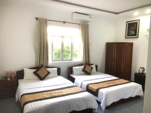 dwa łóżka w pokoju z oknem w obiekcie KHÁCH SẠN PHƯƠNG DUNG w mieście Dak Rơleang